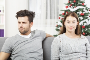 An image of a couple being irritated with each other on a sofa, used to illustrate being divorced & living together at christmas.