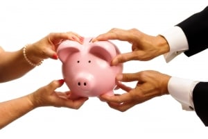 Man and womans hands pulling at a piggy bank to illustrate finances during a divorce